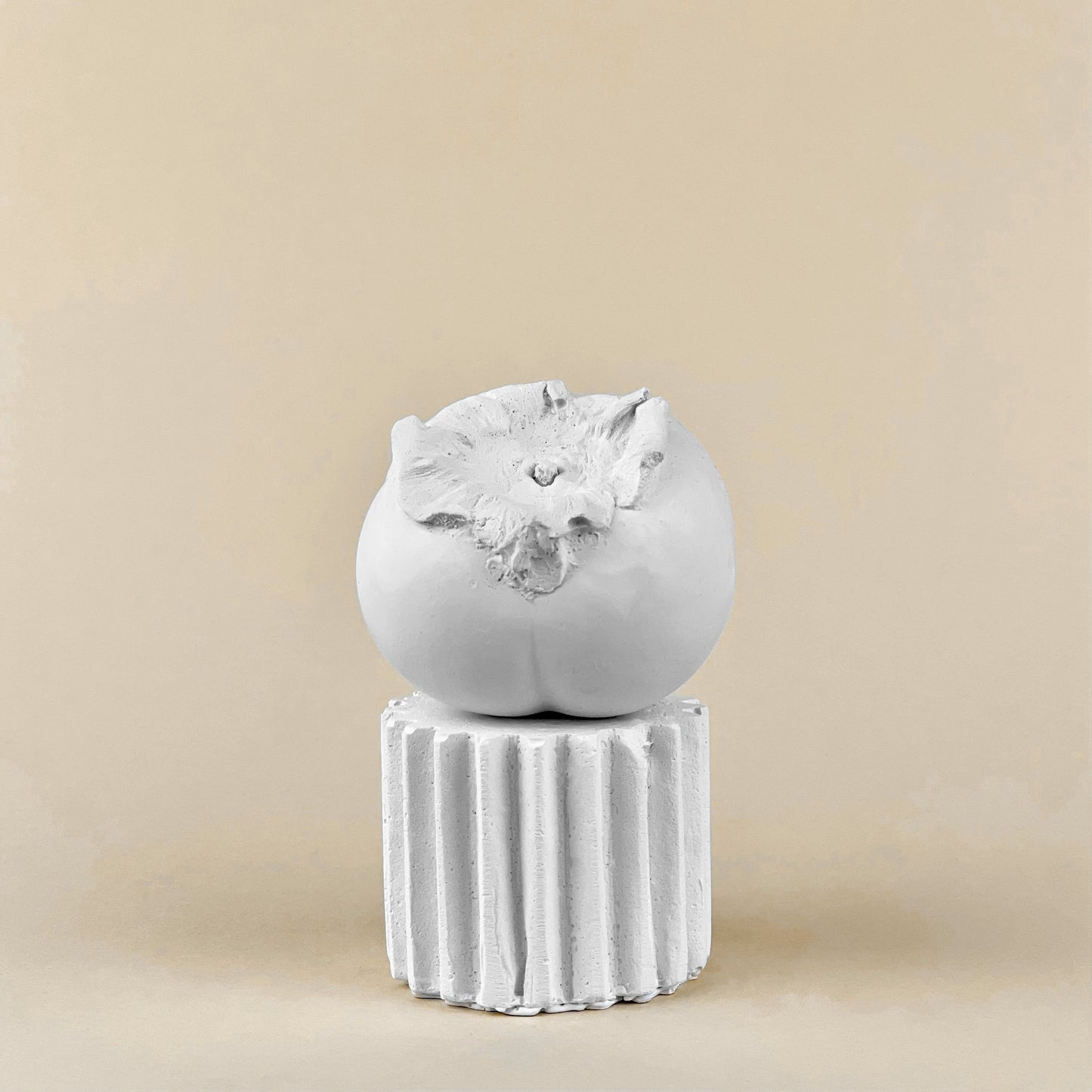 Persimmon made of plaster and fake fruit is all white with small pedestal