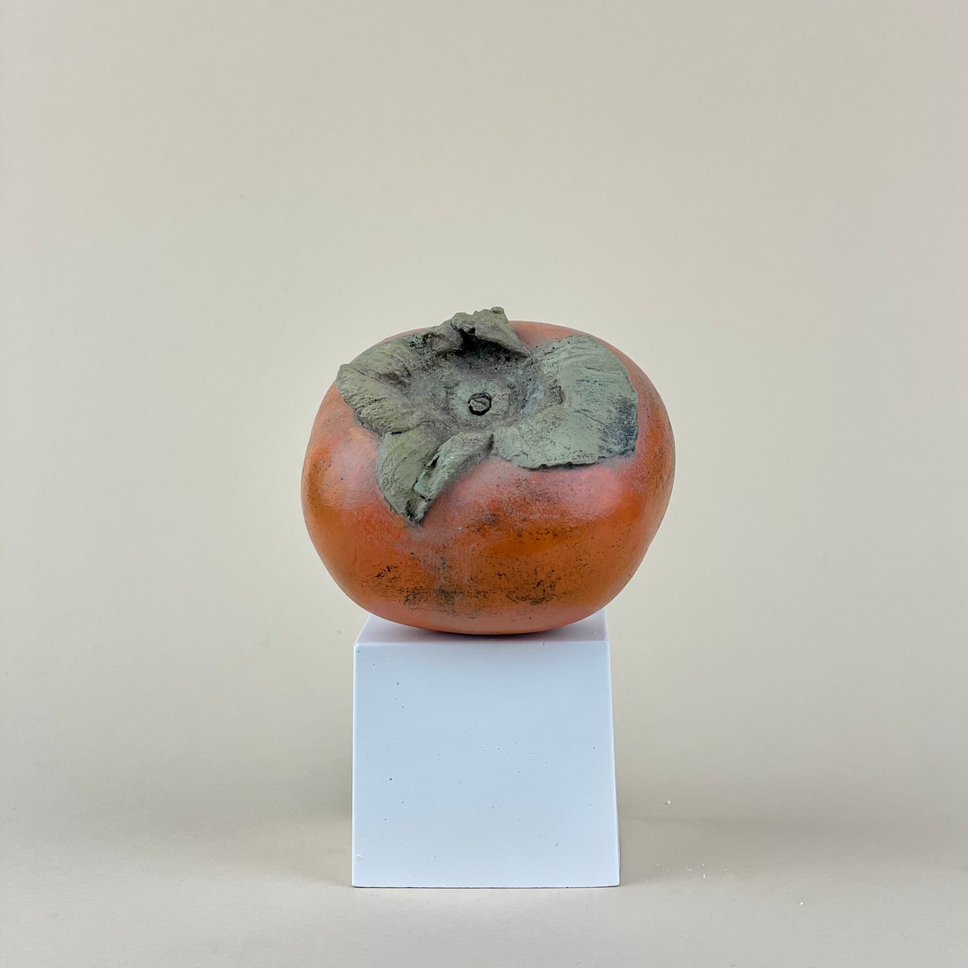 Persimmon made of plaster and hand painted fake fruit and on a plinth